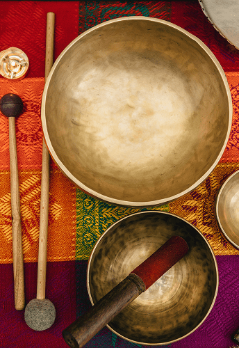 Singing bowls and mallets on colorful fabric.