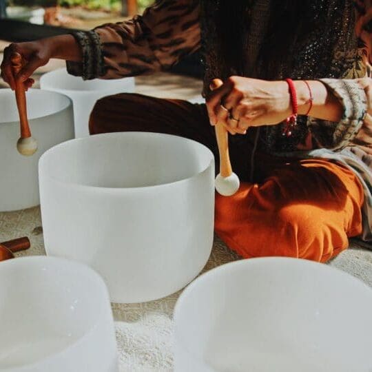 Person playing crystal singing bowls indoors.